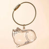 A clear, dog-shaped glass charm attached to a braided gold-colored cord.