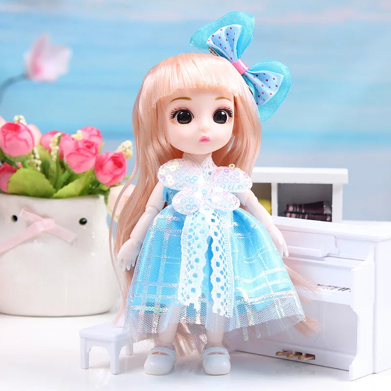 A 17cm articulated princess doll with long blonde hair wearing a blue and white patterned dress, standing next to a white box