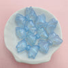 A collection of shimmering light blue mermaid bowknot beads arranged on a white dish.