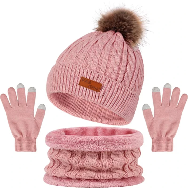 A set of women's knit winter hat, scarf, and gloves in pink with a faux fur pom.