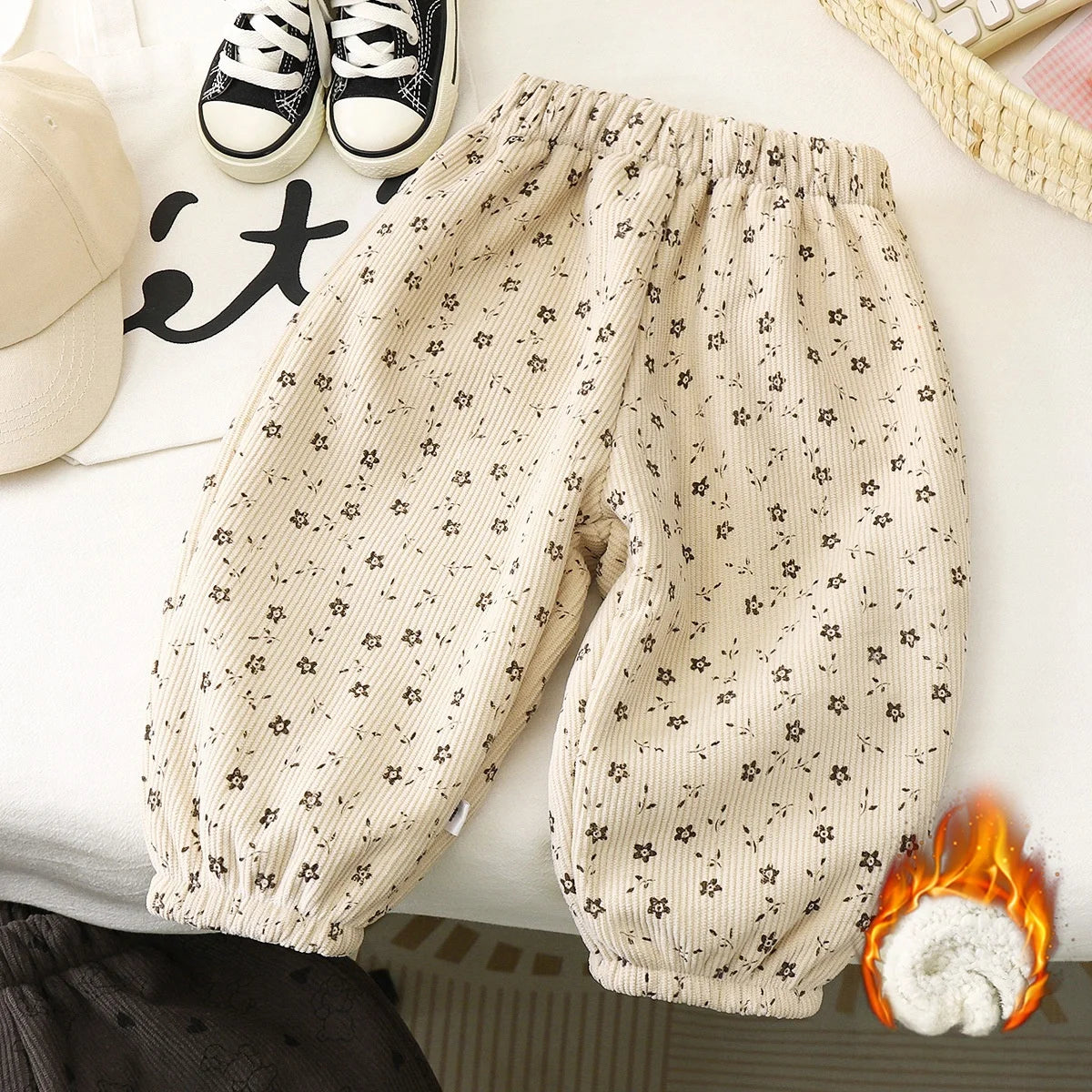 Light beige fleece-lined pants with a small floral print laid out on a white surface.