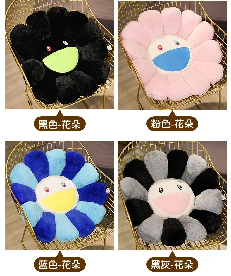 Four variations of large sunflower plush cushions in black, pink, blue, and gray.