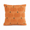 A square orange knitted pillow cover with a repeating pattern of small green ghost pumpkin designs.