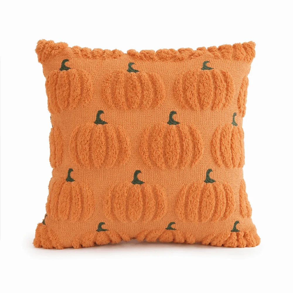 A square orange knitted pillow cover with a repeating pattern of small green ghost pumpkin designs.