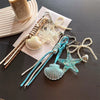 A set of beaded keychains featuring starfish and seashell charms on white and blue cord.
