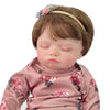 A handcrafted reborn newborn doll with soft silicone body, featuring brown hair and a floral headband.