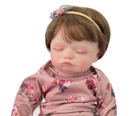 A handcrafted reborn newborn doll with soft silicone body, featuring brown hair and a floral headband.