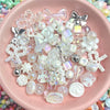 A collection of clear and iridescent acrylic bow and flower beads for DIY jewelry making displayed in a pink bowl.