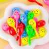 A collection of colorful mini maracas shaker toys in various bright colors, including yellow, pink, green, and blue.
