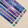 A collection of 27 iridescent star-shaped strips in various colors laid diagonally on a light background.