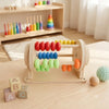 A wooden Montessori busy board for toddlers featuring colorful gears, switches, and sensory components.