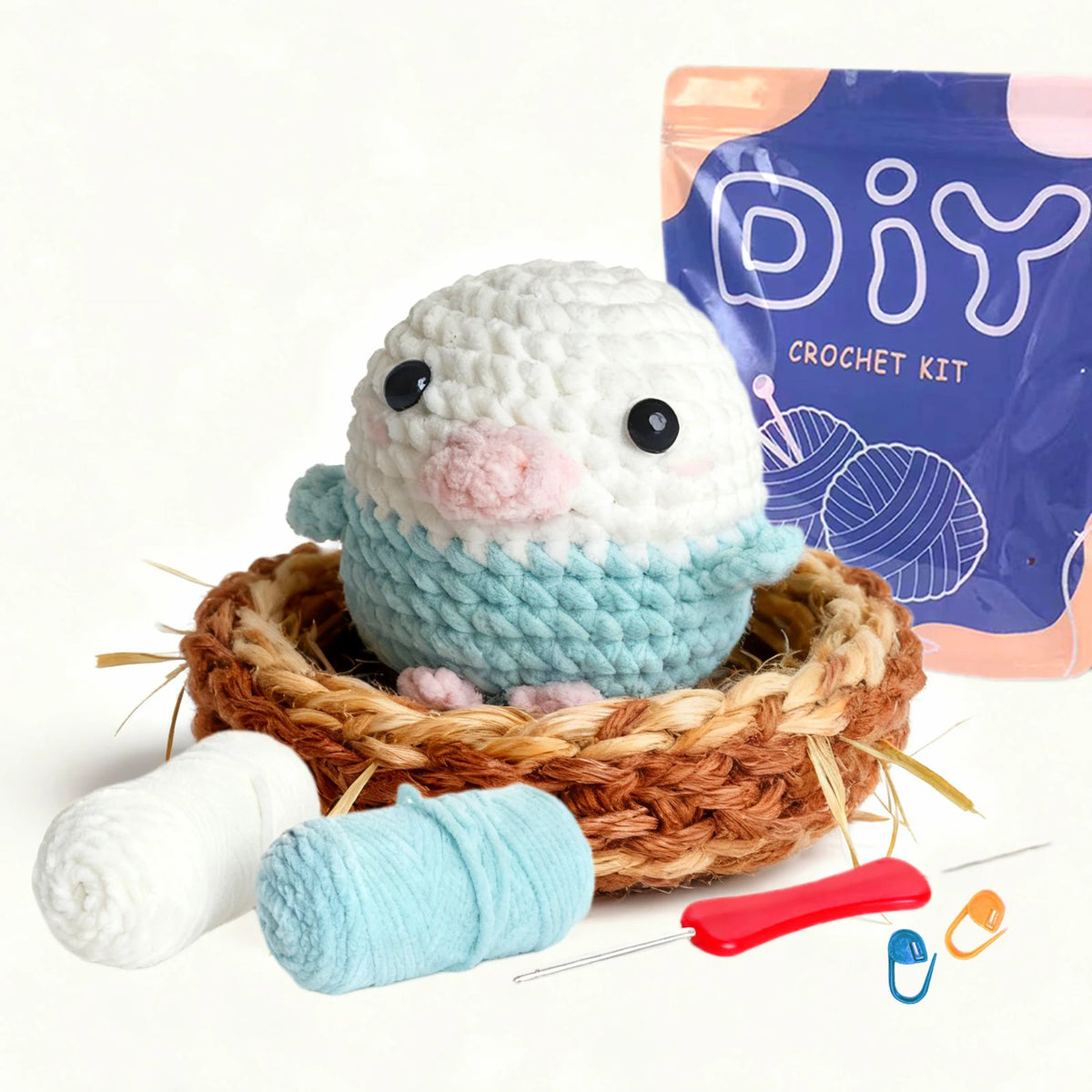 A beginner bird crochet kit featuring a white and light blue amigurumi figure, yarn, and a purple packaging bag.