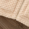 A close-up of a beige plush hooded winter jacket fabric resting on a wooden surface.