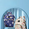 Two cartoon print waterproof diaper bags, one purple and one pink, displayed in a light blue setting.