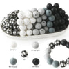 A collection of soft food-grade silicone beads in various colors including white, gray, and black, displayed on a white plate