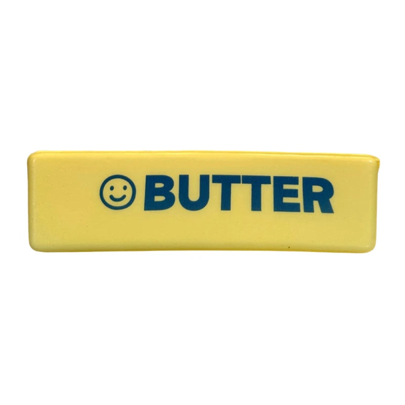 A yellow rectangular butter squishy stress relief fidget toy with the word BUTTER printed in dark blue.