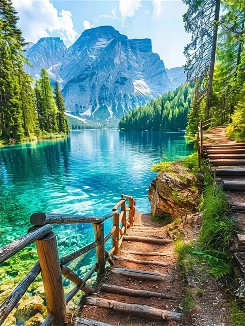 A scenic view of a turquoise mountain lake surrounded by lush green forests and jagged peaks.
