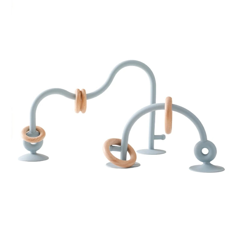 A light gray silicone teething toy with curved arms and rings for baby development.