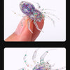 A purple and iridescent realistic spider soft bait lure with legs held by a hand.