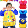 A child wearing a yellow waterproof art and baking apron with long sleeves, featuring colorful paint splatters.
