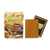 A box of Dragon Shield gold matte card sleeves next to a single gold matte card sleeve.