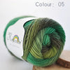A ball of green merino wool yarn, color 05, is shown on a wooden surface.