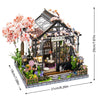 A detailed miniature dollhouse kit featuring a wooden structure, floral accents, and warm lighting.