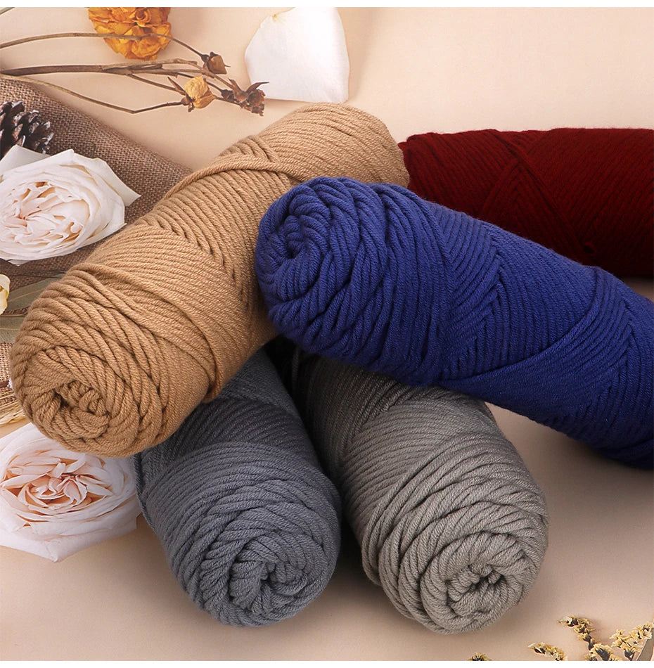 A collection of three skeins of soft cotton blend yarn in shades of beige, blue, and gray for knitting and crochet.