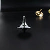 A silver metal fidget spinner resting on a dark surface next to a gold-colored object.
