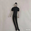 A black poseable plush doll figure standing upright against a white background.