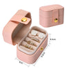 A pink portable leather jewelry storage box with a lid, showing various pieces of jewelry inside.