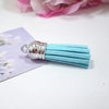 A bundle of light blue velvet tassels with silver metal findings resting on a purple card.