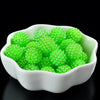 A white bowl filled with bright green acrylic pearl beads for jewelry making.