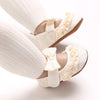 A pair of white soft cotton baby walking shoes with anti-slip soles shown from the side.