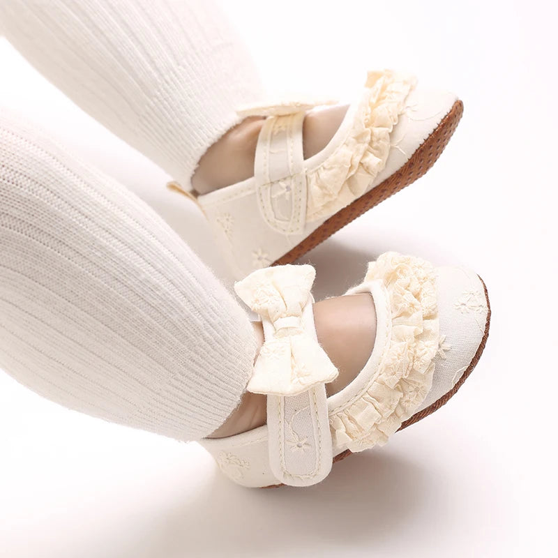 A pair of white soft cotton baby walking shoes with anti-slip soles shown from the side.