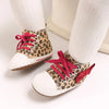 A pair of leopard print soft sole baby sneakers with white socks shown on a light background.