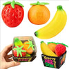 A set of three fruit squishy fidget toys: a red strawberry, an orange, and a yellow banana, displayed in packaging.