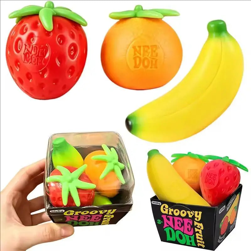 A set of three fruit squishy fidget toys: a red strawberry, an orange, and a yellow banana, displayed in packaging.