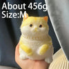 A yellow cat shaped squishy stress relief toy being held in a hand.