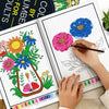 A hand is coloring a page from a color by number book featuring floral designs with colored pencils.