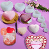 A collection of white and pink silicone heart molds for DIY crafts, including a glass filled with pink ice cubes.