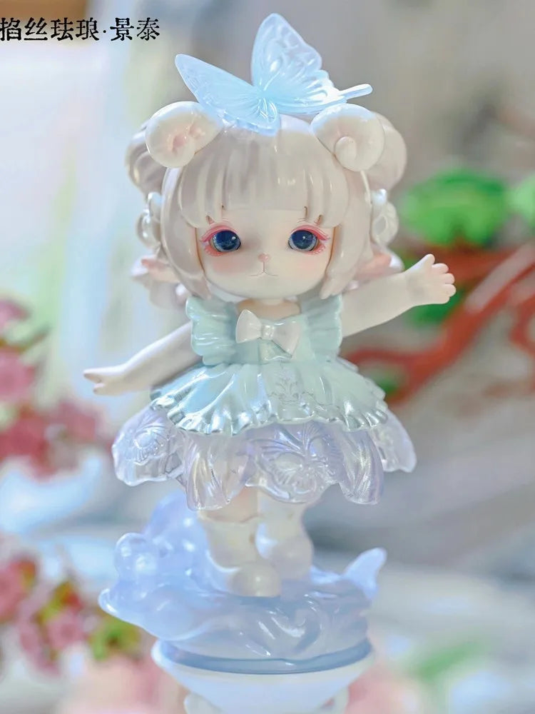 A cute figurine of a girl with light pink hair and blue eyes wearing a light blue dress and a butterfly accessory.