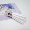 White velvet tassels with silver metal tips displayed on a purple floral background