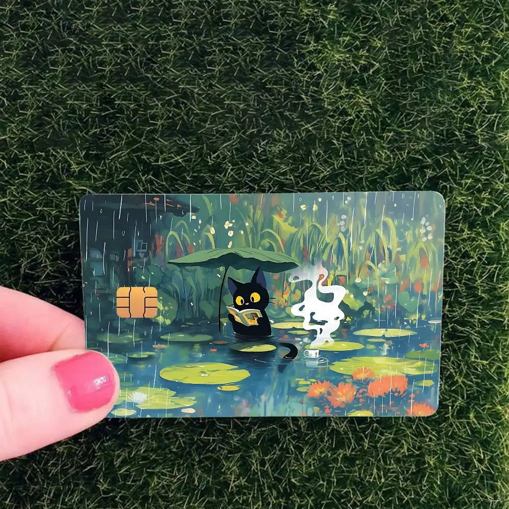 A card featuring a cute black cat in the rain amidst green foliage and water ripples.