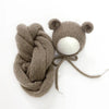 A knitted bear hat and wrap set in a taupe color with a white pom-pom.