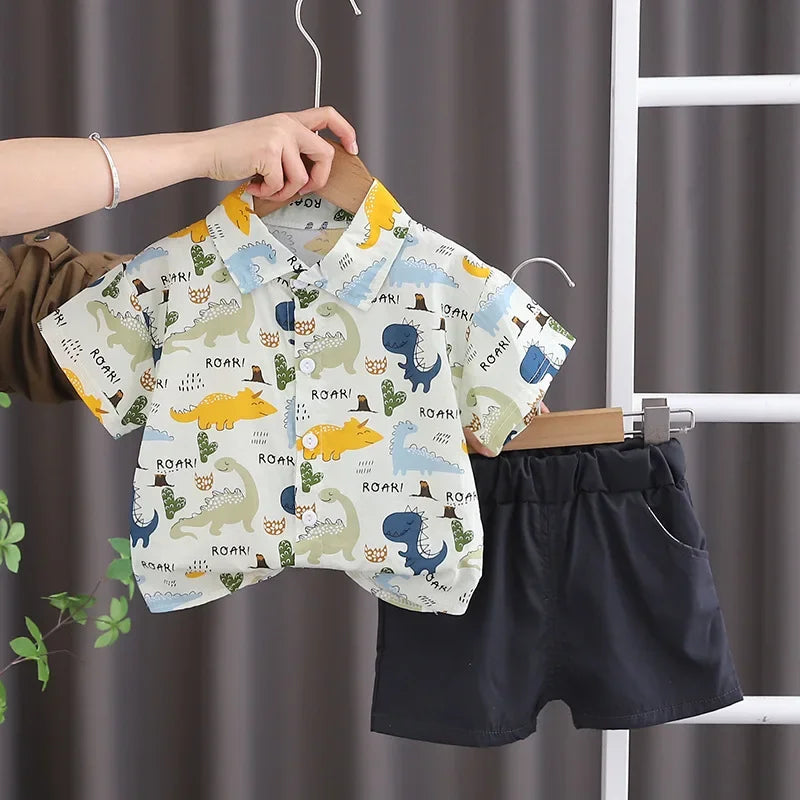 A boy's cotton summer short sleeve t-shirt and shorts set featuring a dinosaur pattern hanging on a white rack.