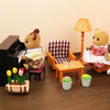 A miniature dollhouse set featuring forest animal figures, furniture, and a lamp in a light-colored room.
