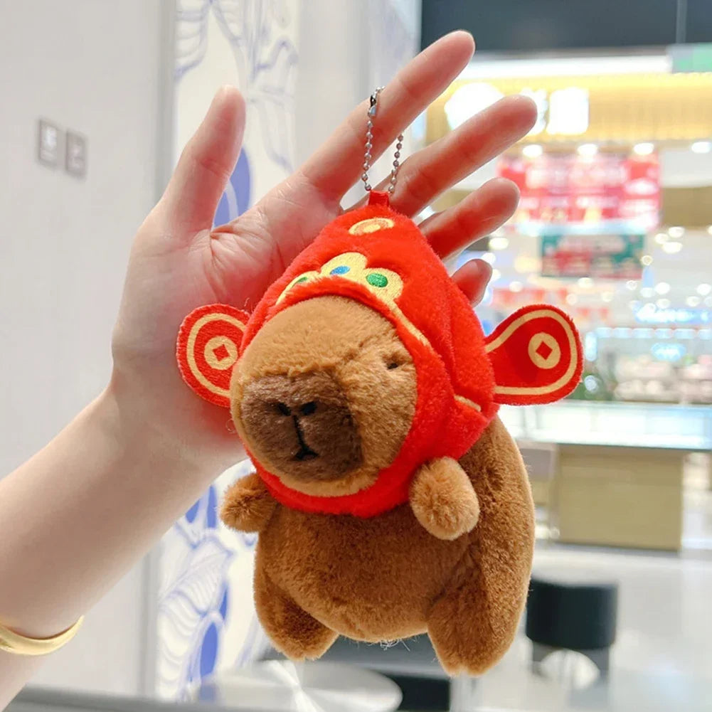 A fluffy orange capybara plush toy is being held in a person's hand.