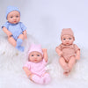 A set of three realistic soft vinyl reborn baby dolls wearing blue, pink, and tan outfits lying on white fluffy material.