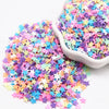 A pile of colorful polymer clay sprinkles in various pastel colors like pink, purple, blue, and yellow scattered on a white s